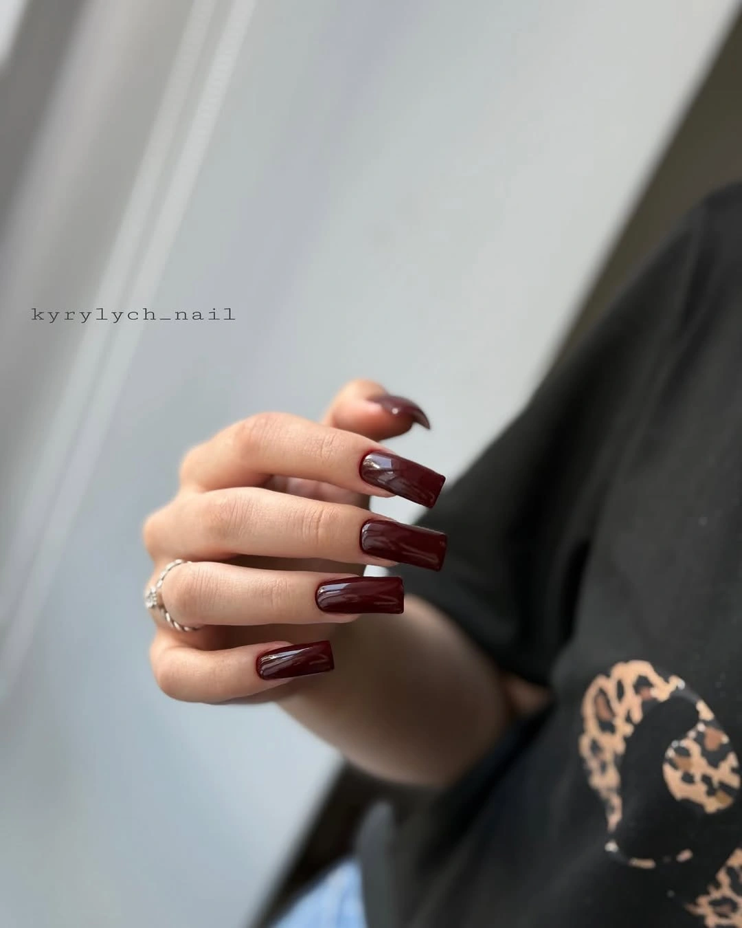Glossy deep wine square nails framed by black lace and pale skin