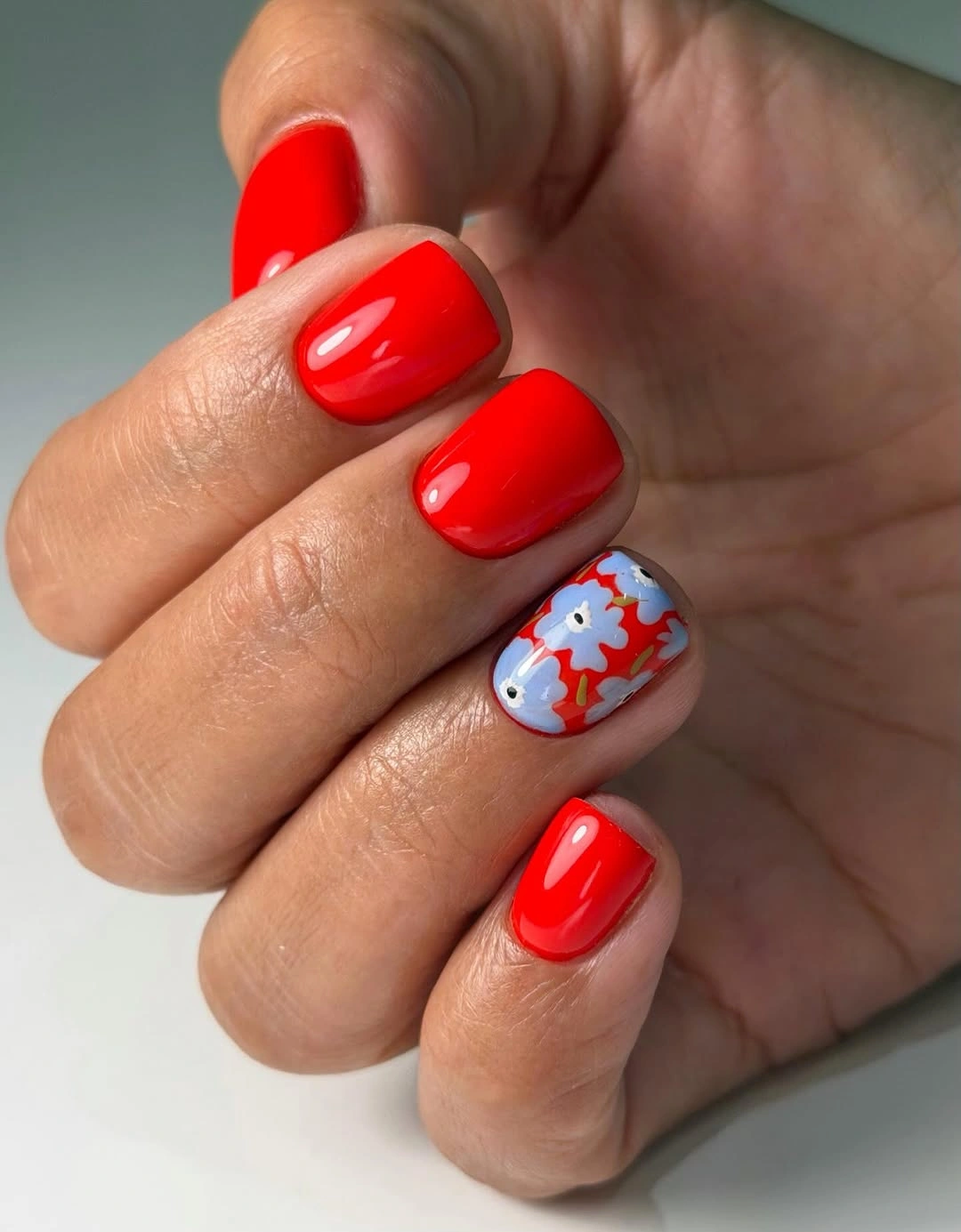 Glossy cherry red short nails with one blue accent