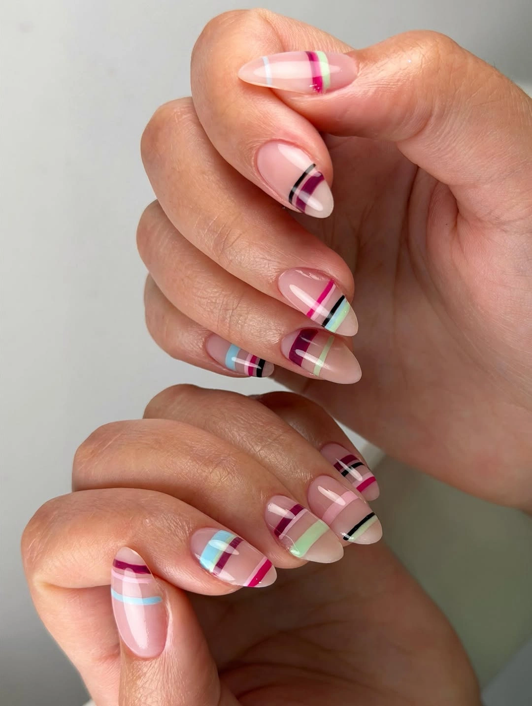Long sheer pink almond nails with colorful striped tips