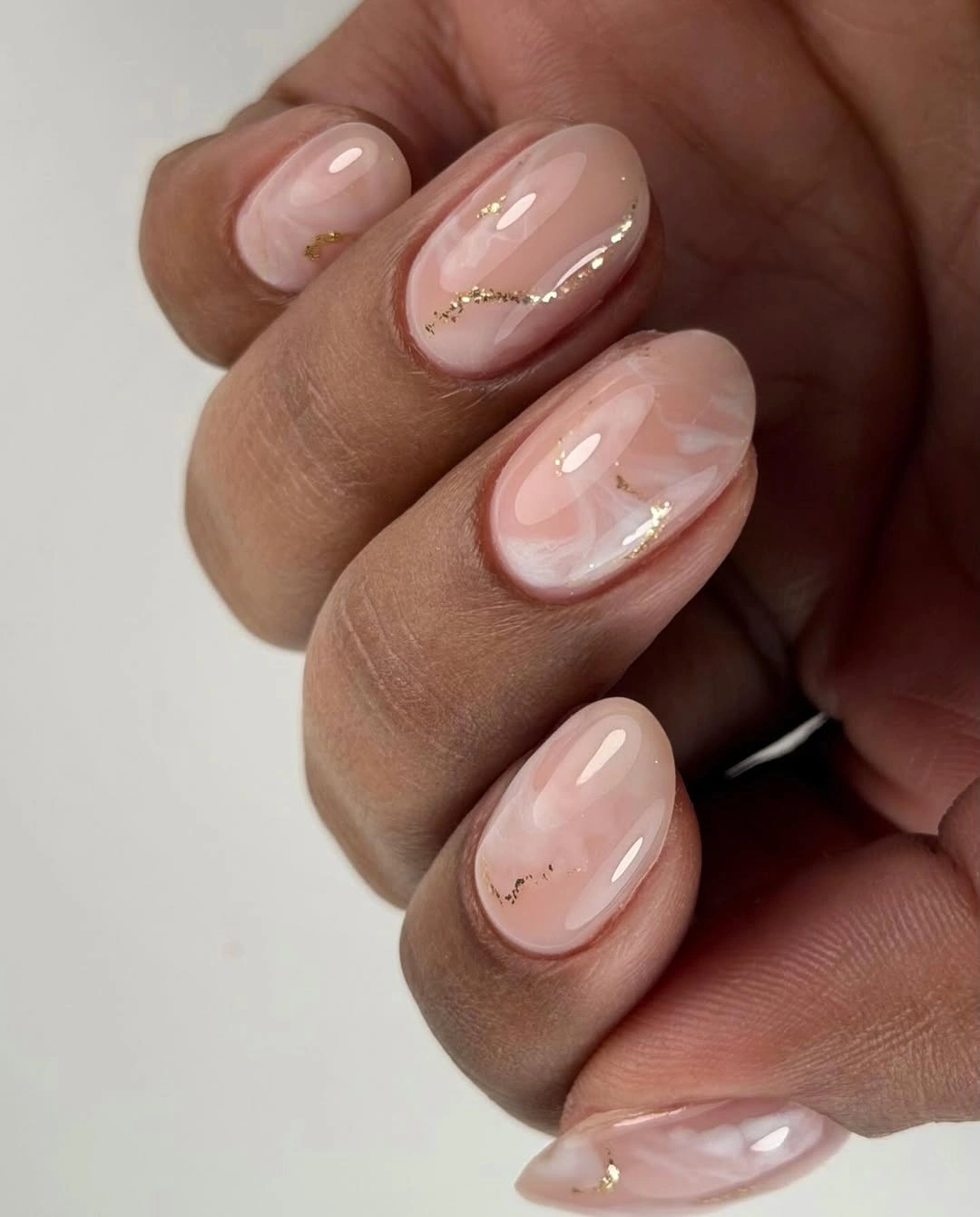 Short oval sheer nude nails with fine gold contours