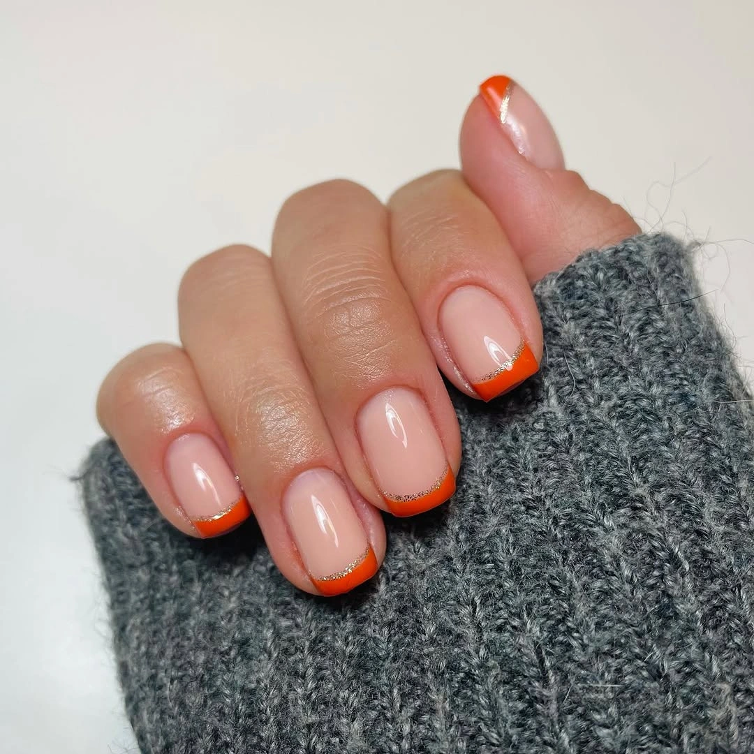 Short pink nails with thin orange French tips