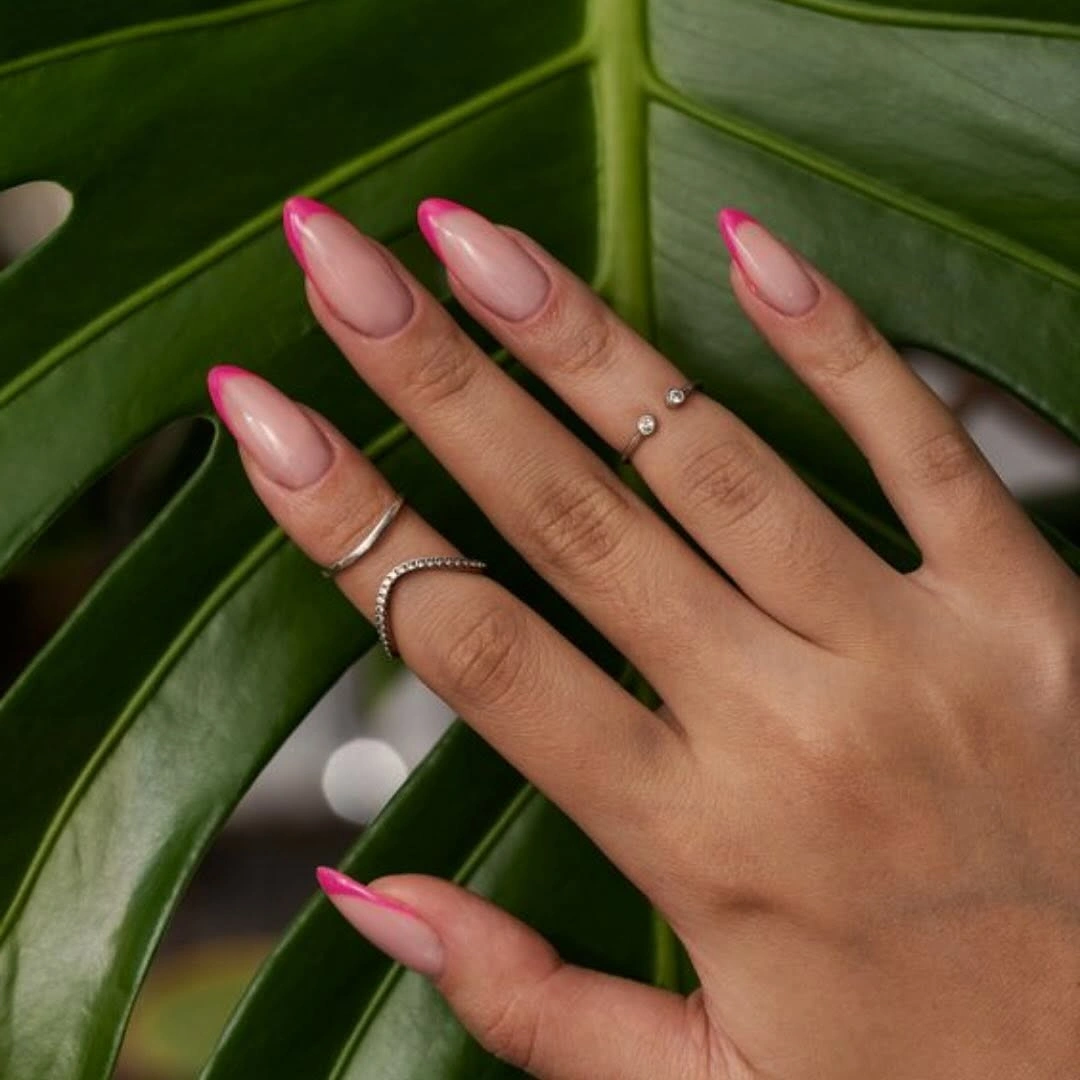 Long almond nails with pale nude bases and bright pink French edges