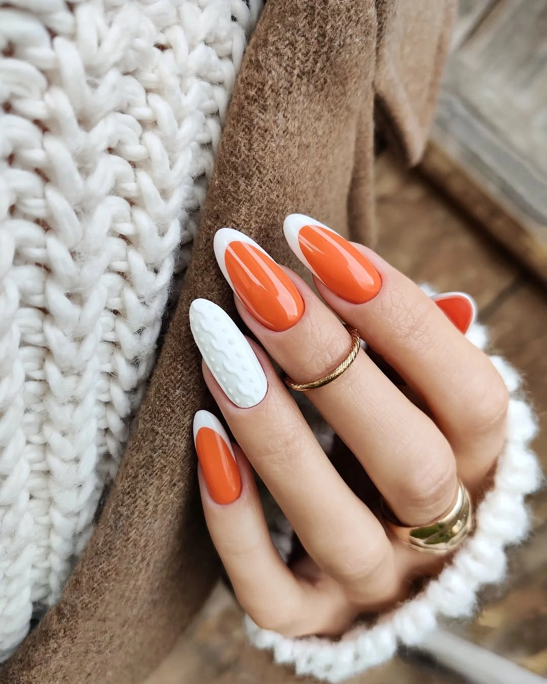 Medium almond nails with orange tips and a pale textured-looking accent