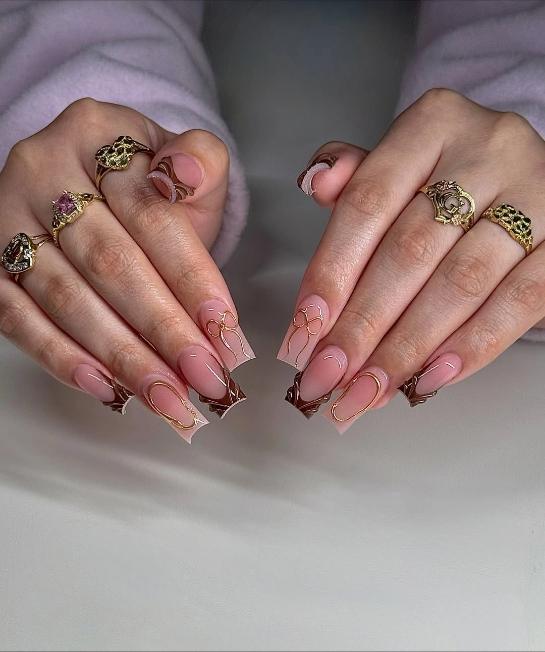 Long square nails with pink translucent bases and small white brown and burgundy corner accents