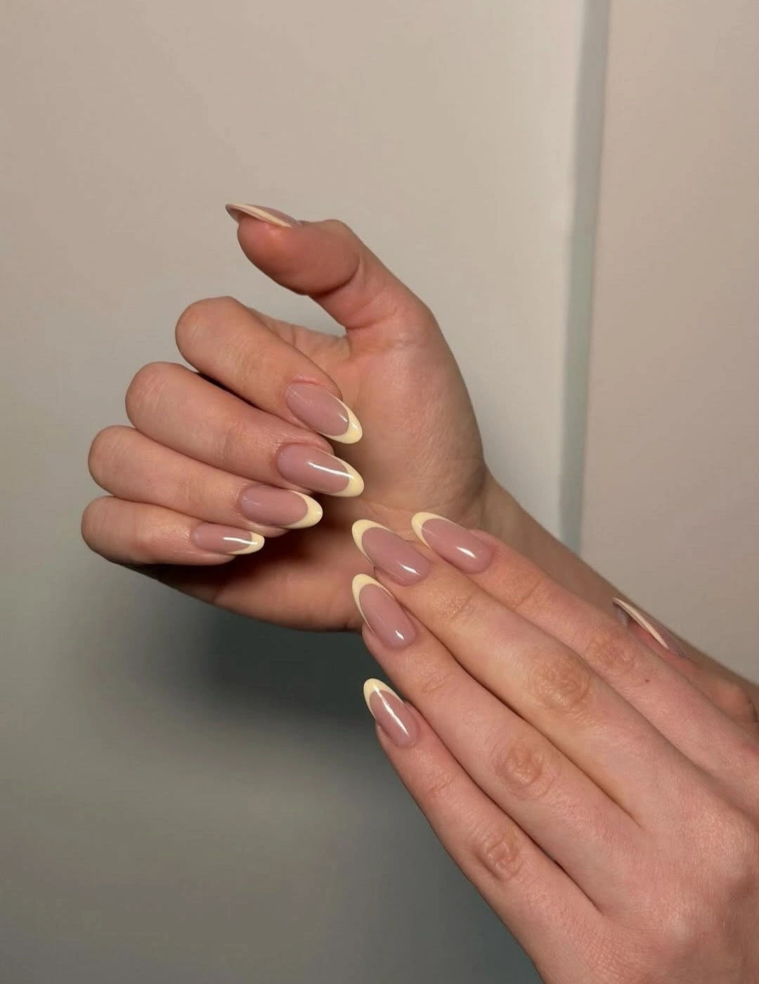 Medium almond nails with translucent nude bases and tiny cream French edges
