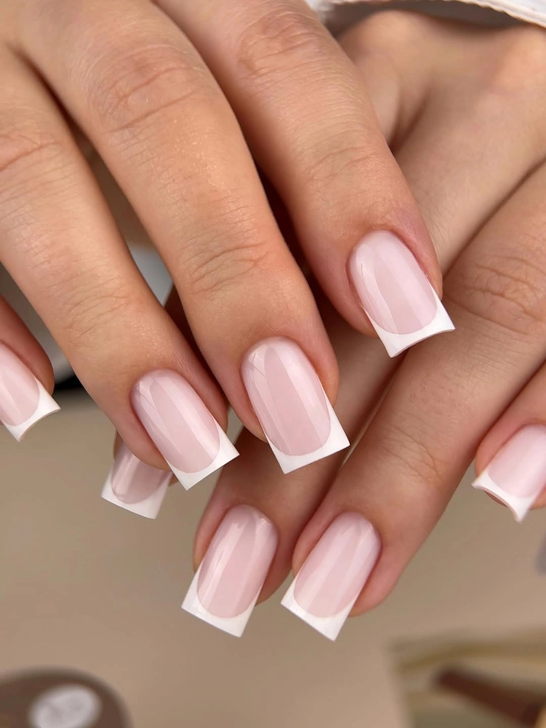 Long square nails with sheer blush bases and broad opaque white French tips