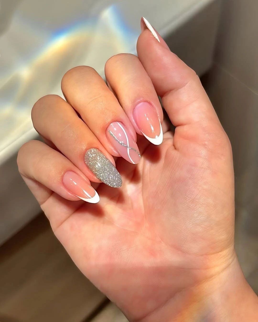 Blush almond nails with white French tips and one silver glitter accent
