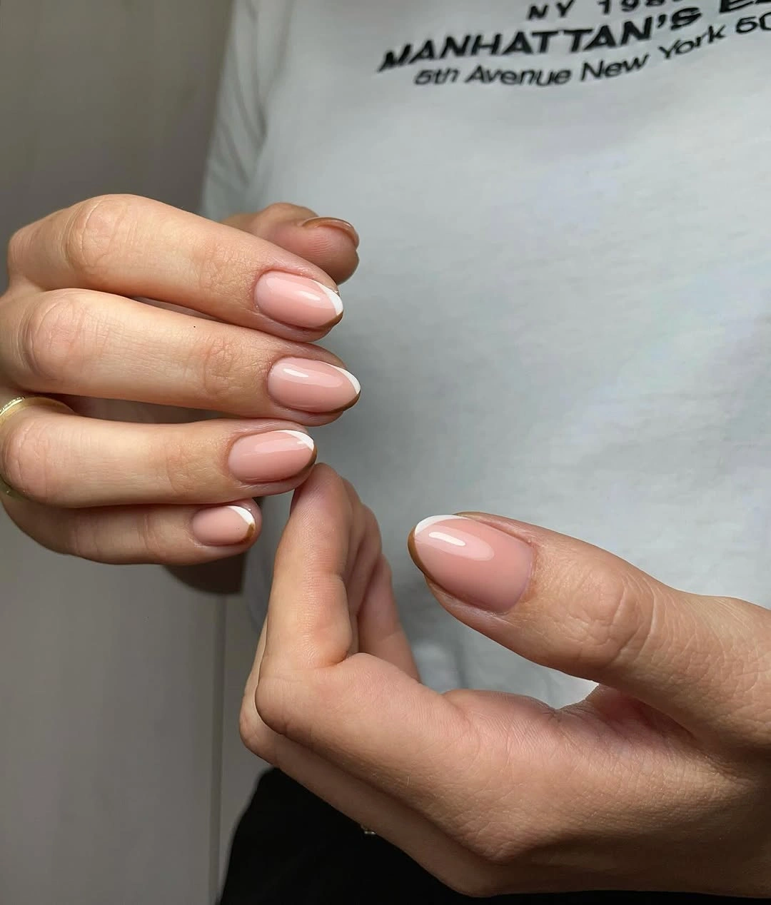 Short almond nails with a pale nude pink base and soft white edges