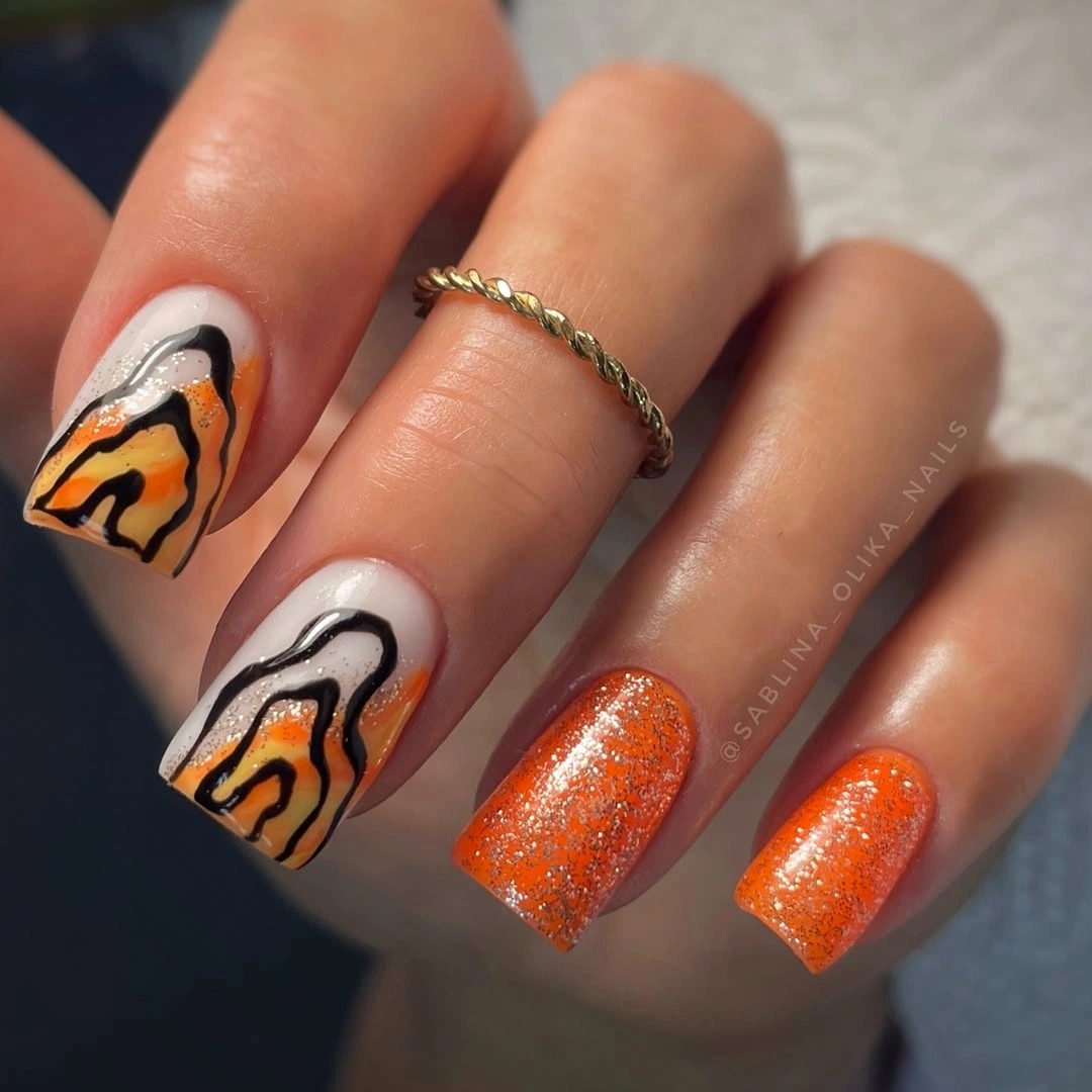 Short orange glitter nails with black curved accent lines