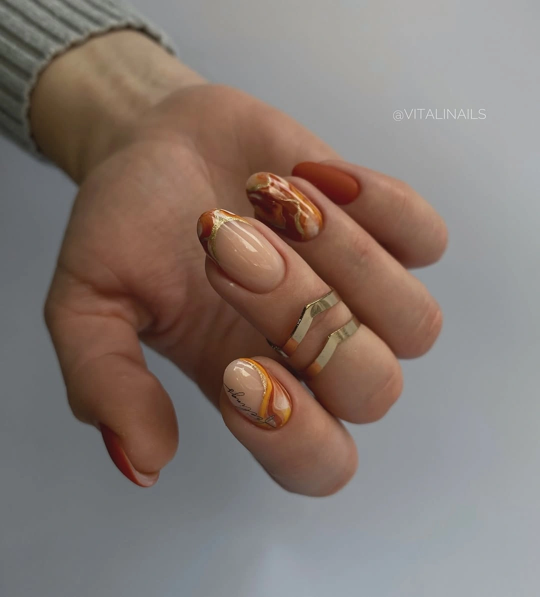 Medium oval nails with caramel swirls and warm metallic edges