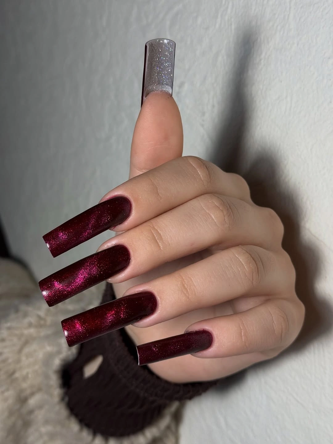 Long burgundy shimmer nails with one silver glitter accent