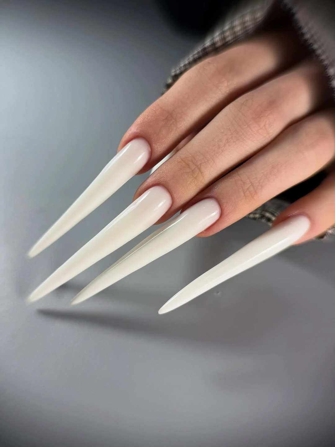Very long creamy white stiletto nails with glossy blank surfaces