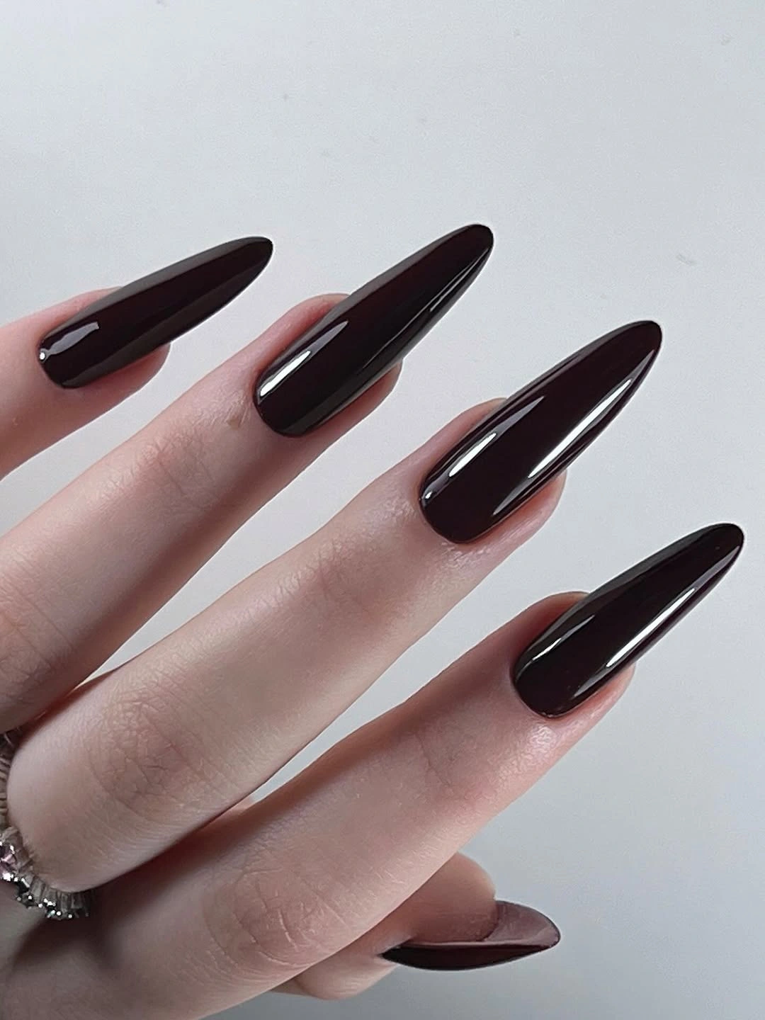 Deep espresso glossy almond nails in a long clean silhouette