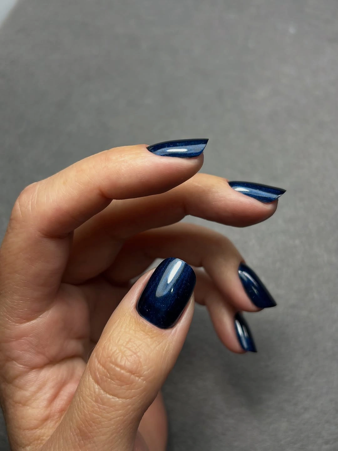 Glossy navy almond nails in a deep blue shade