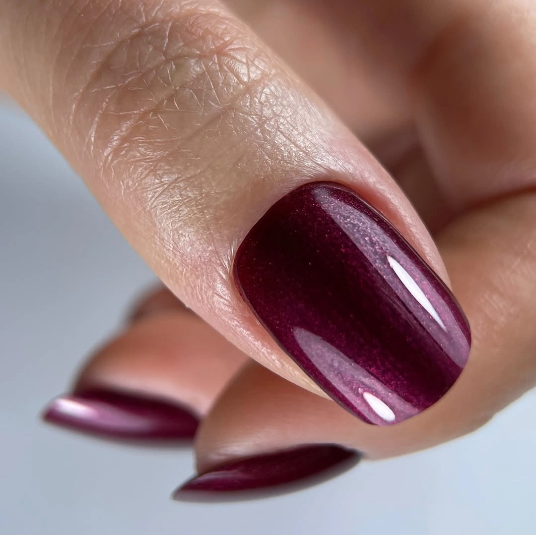 Long almond nails in deep burgundy with reflective sheen