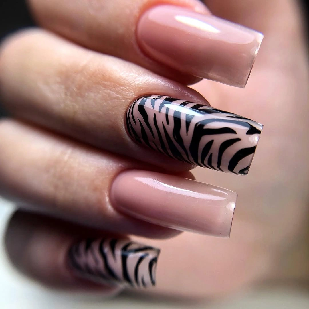 Long square blush-pink nails with black and white zebra accents