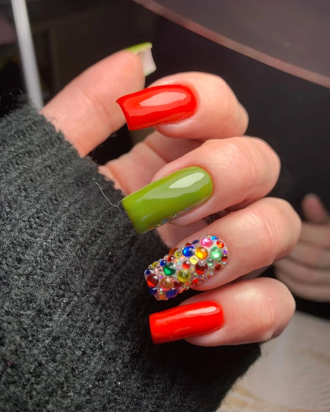 Long square red and green nails with one multicolor accent