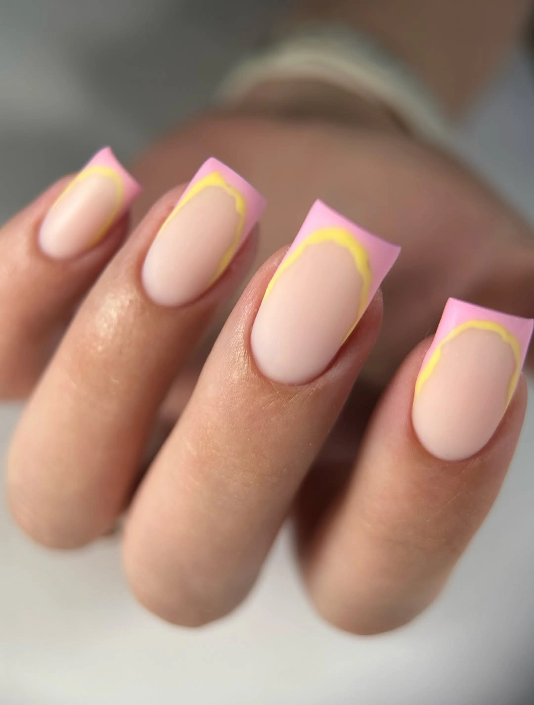 Short soft-pink square nails with slim acid-yellow French outlines