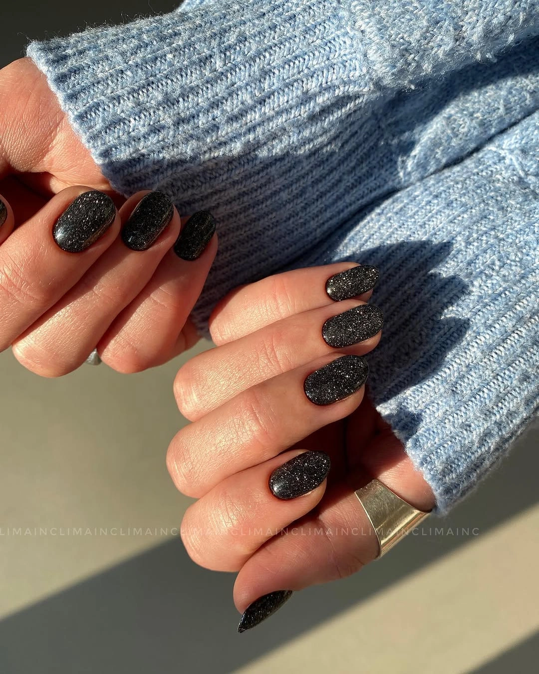 Short-to-medium black almond nails with fine scattered sparkle