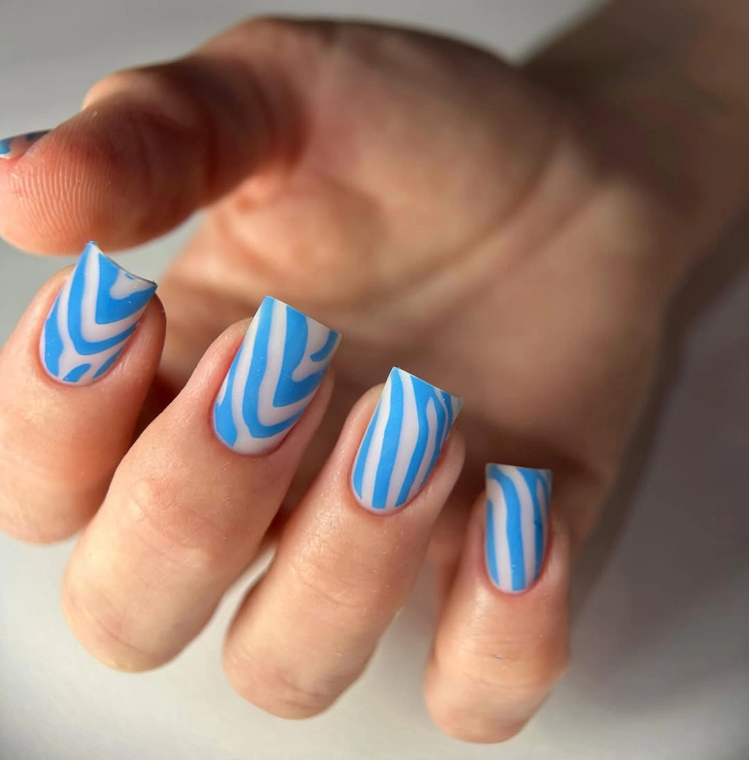 Short rounded nails with blue and white vertical wavy stripes