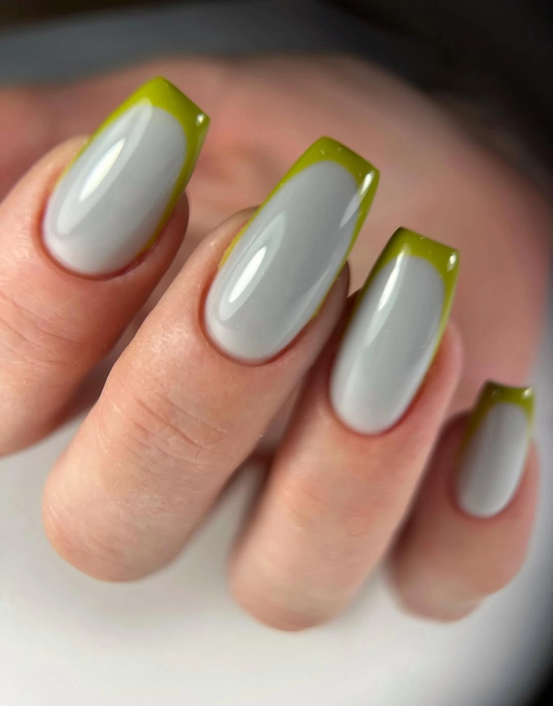 Short glossy cool neutral nails with olive green tips