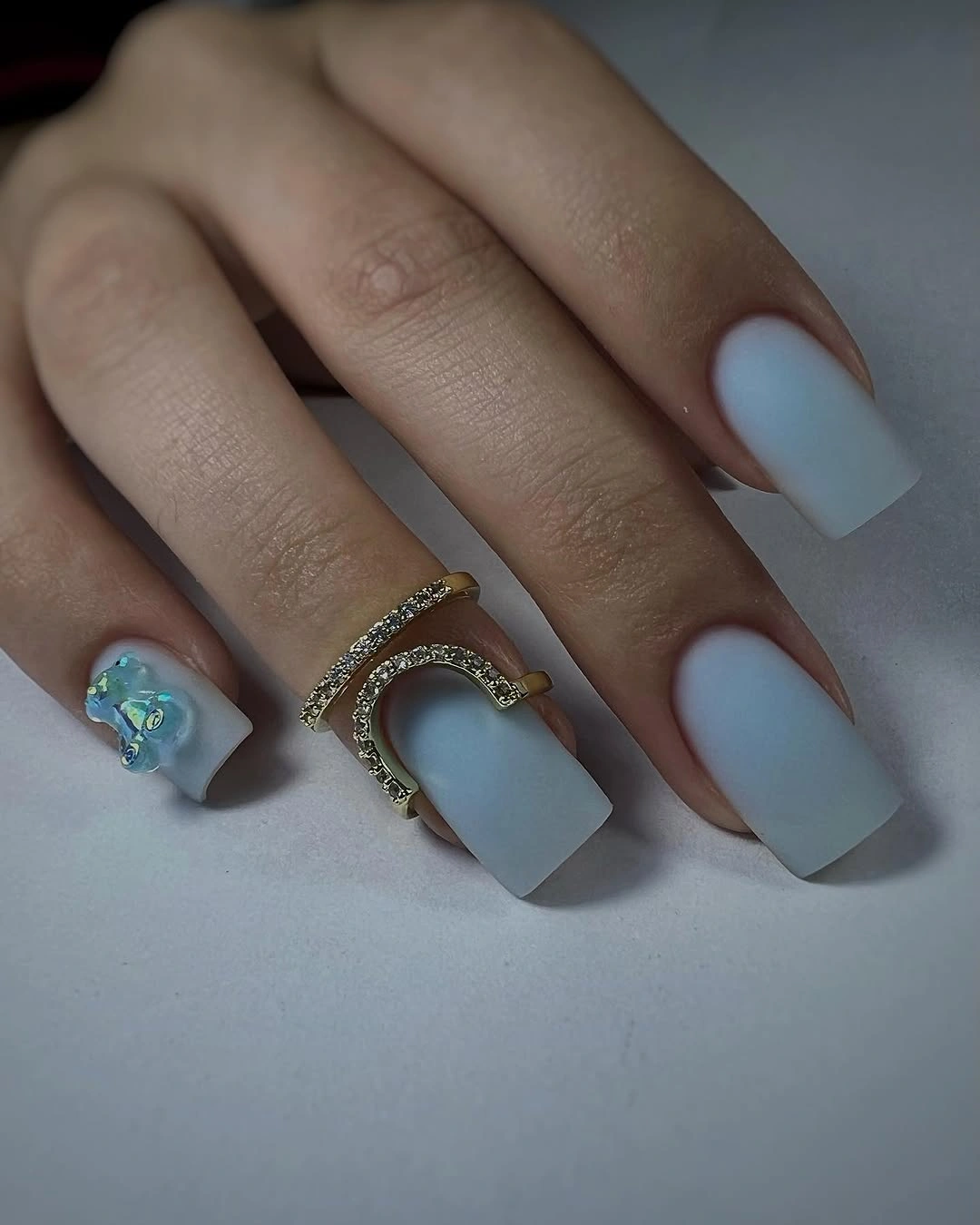 Soft pale-blue short nails with one blue-green and gold accent
