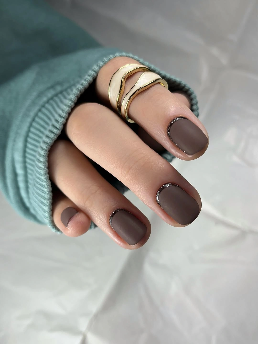 Muted taupe-brown rounded-square nails with gold rings