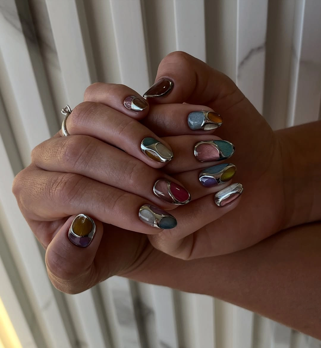 Long almond jewel-tone nails with curved reflective bands