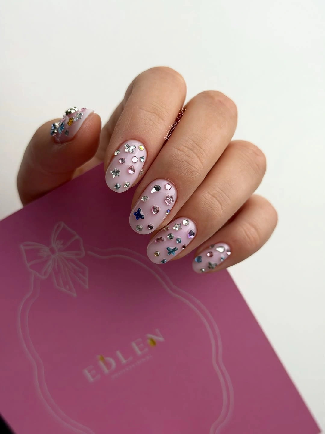 Long almond dusty pink nails with clustered reflective embellishments