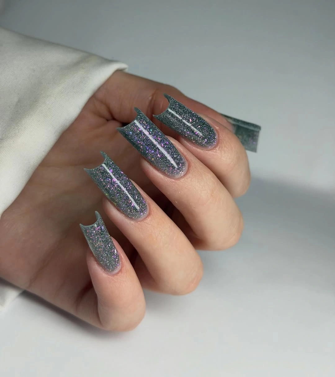 Long tapered square nails covered in cool silver-blue glitter