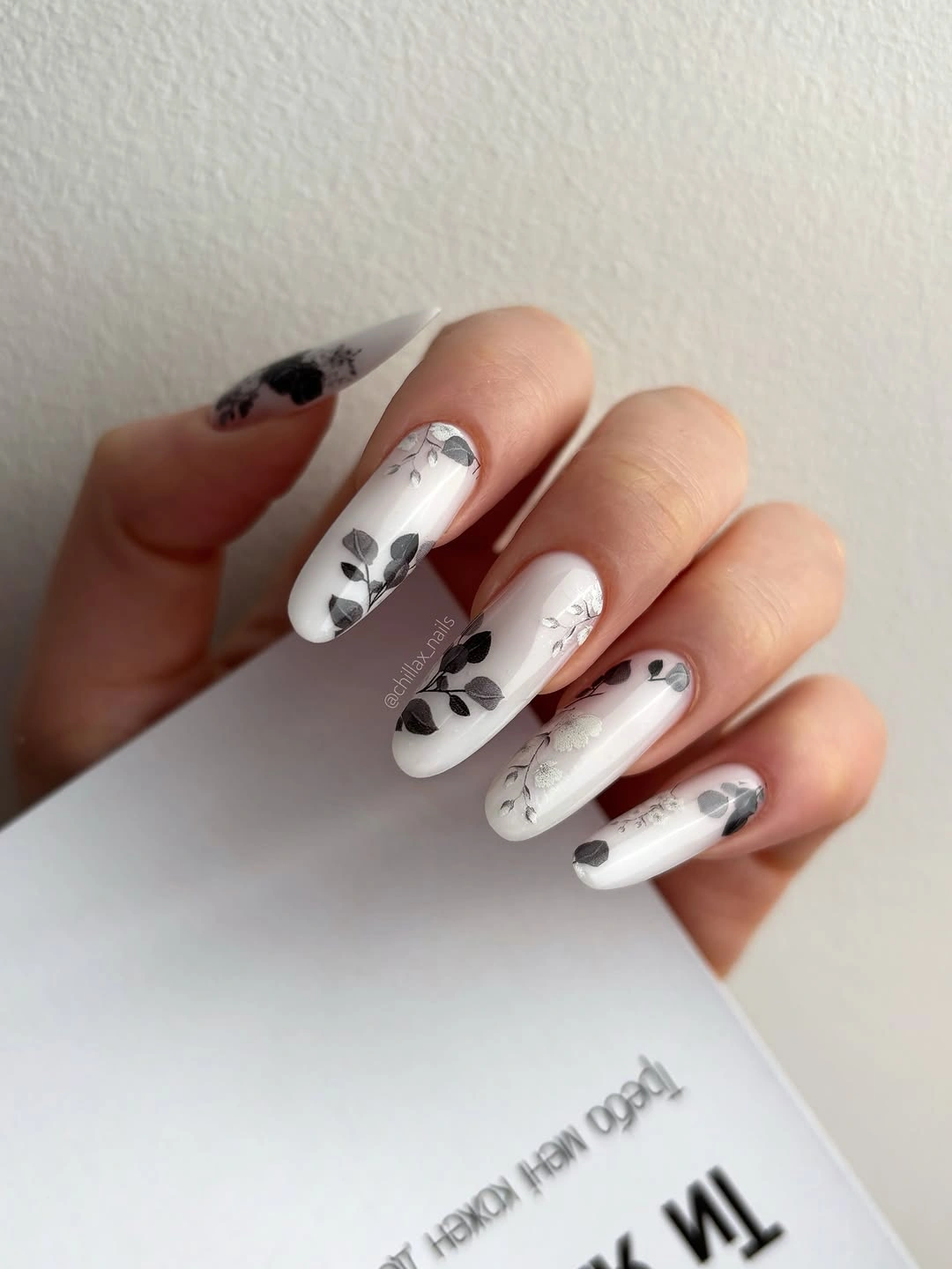 Long almond milky nails with black botanical line art