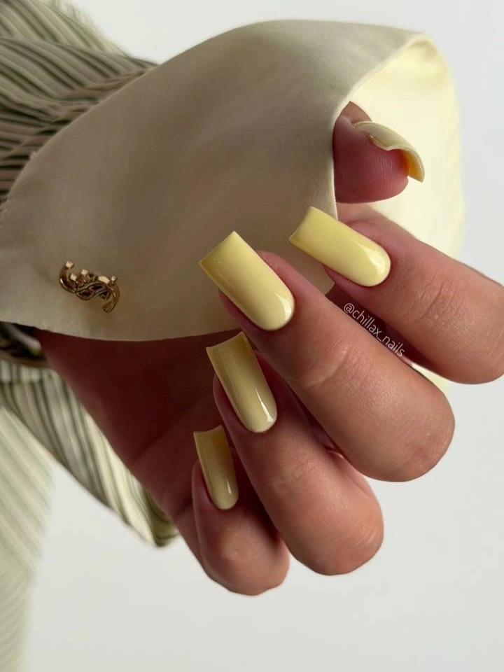 Long square nails in an even pale butter yellow shade