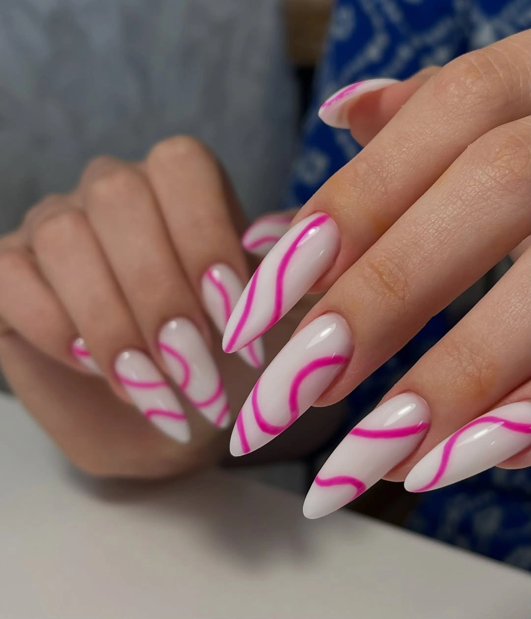 Medium almond nails with white bases and hot pink wavy stripes