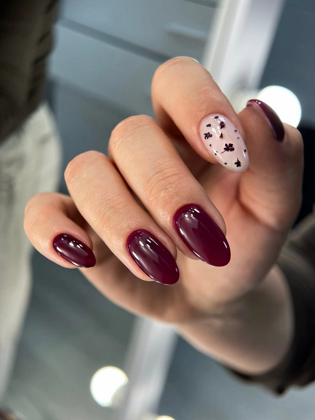 Medium oval nails in berry red with a pale dotted accent