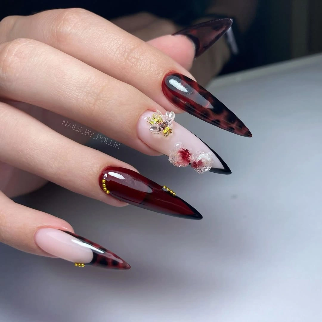 Long dark stiletto nails with one pale floral-like accent nail