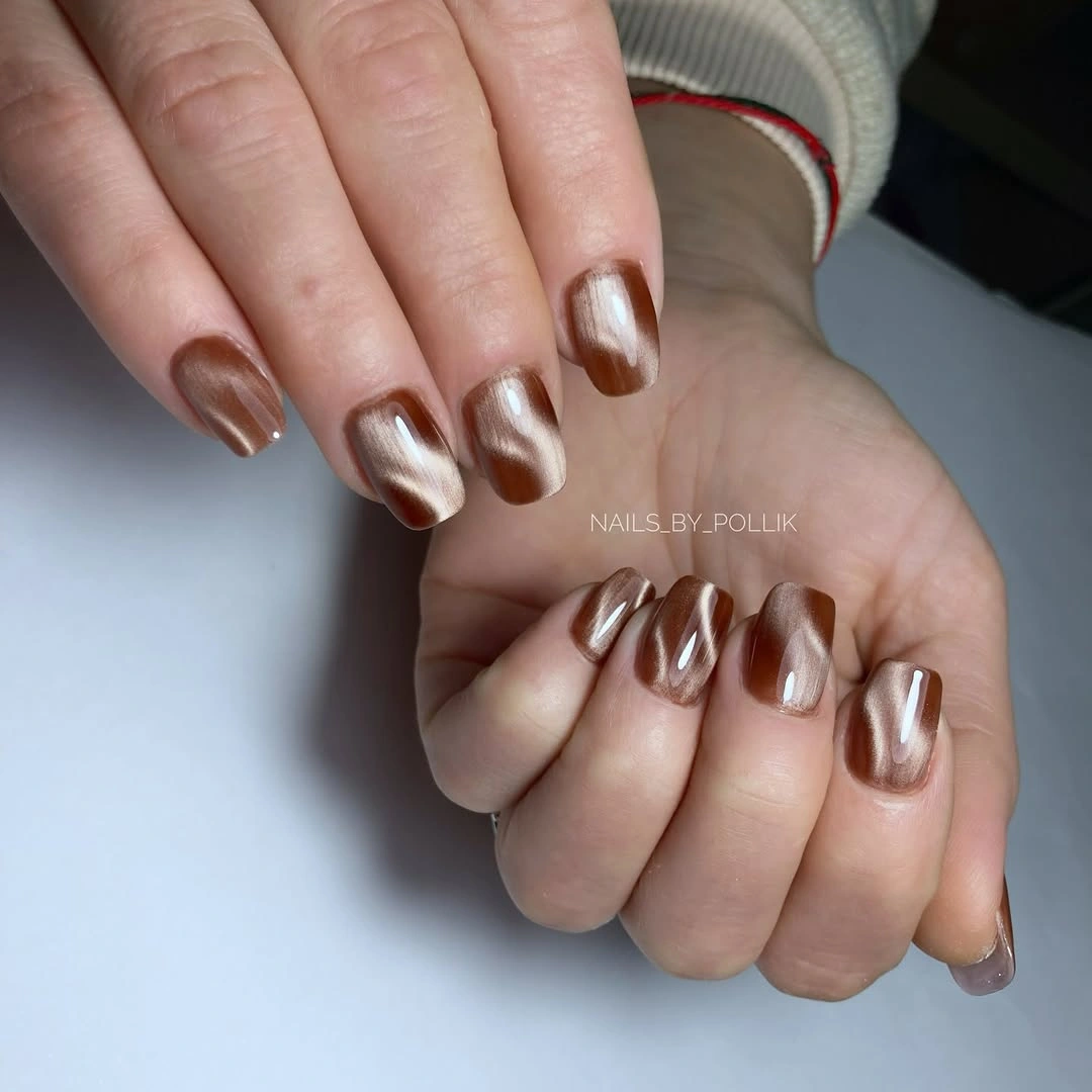 Short square nails covered in a reflective bronze metallic finish