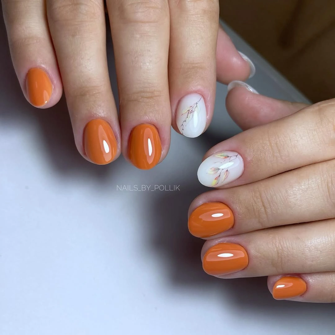 Short glossy orange square nails with two pale detailed accents