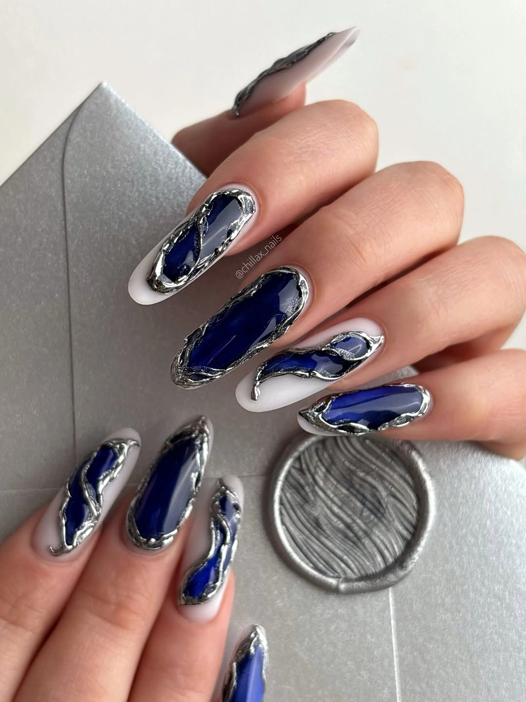Long almond nails with deep blue centers and silver curved borders
