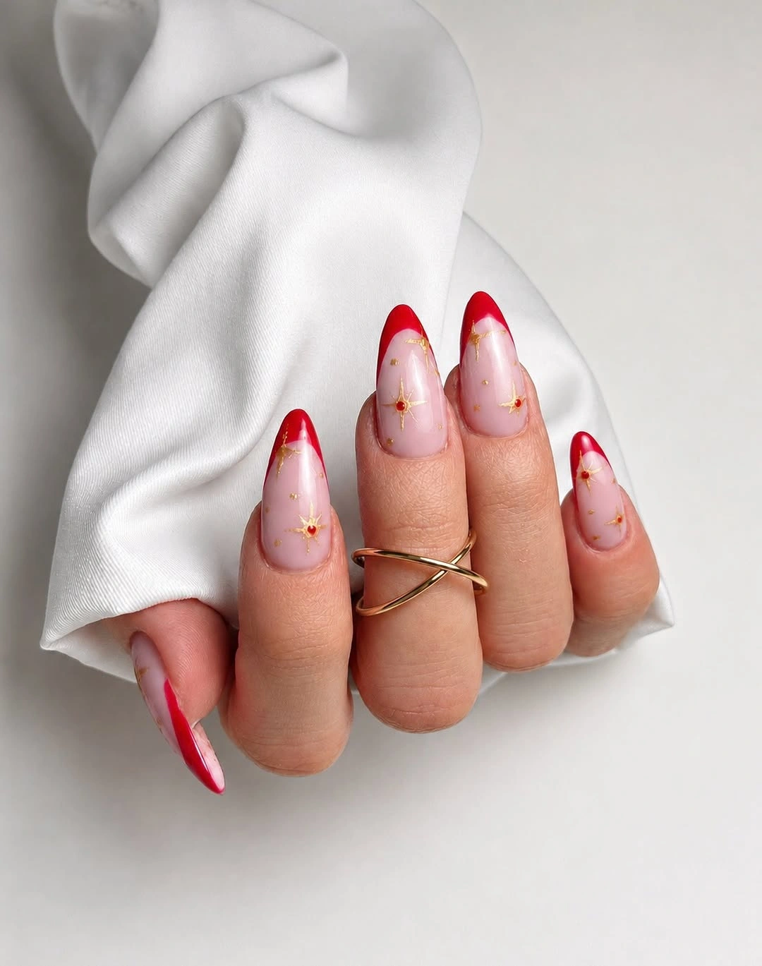 red French almond nails with gold starburst accents