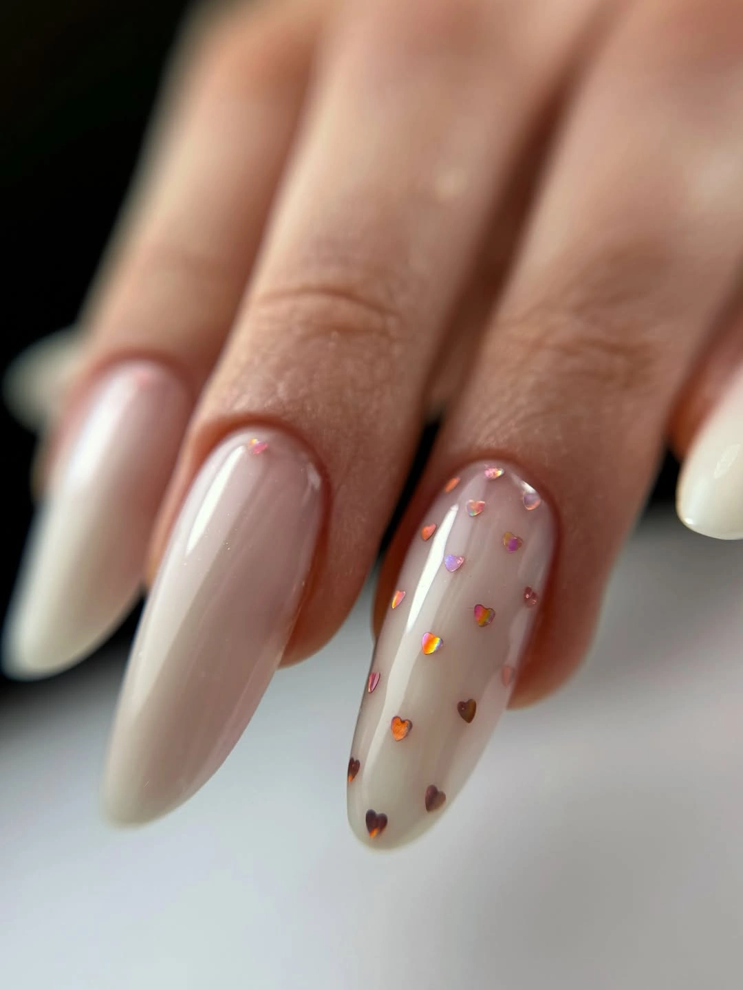 milky almond nails with tiny iridescent hearts