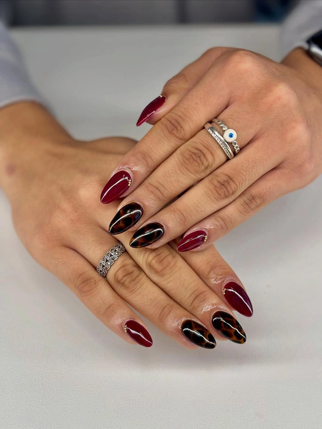 Medium almond nails in burgundy black and red with a small pale accent