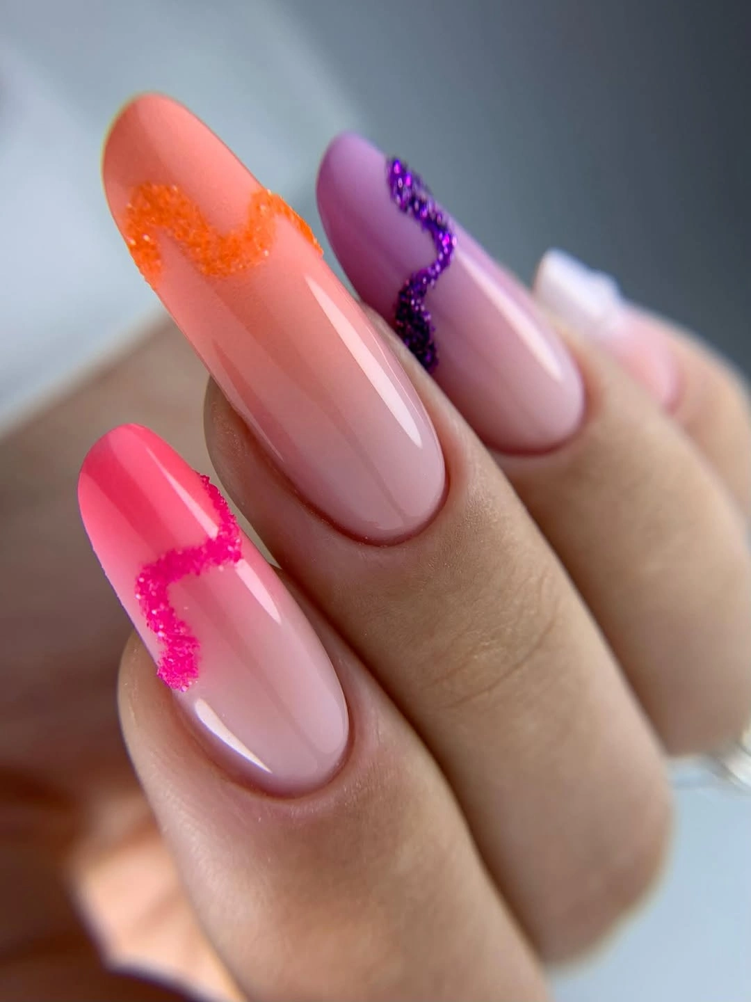 Long almond nails with a translucent pink base coral and purple tips