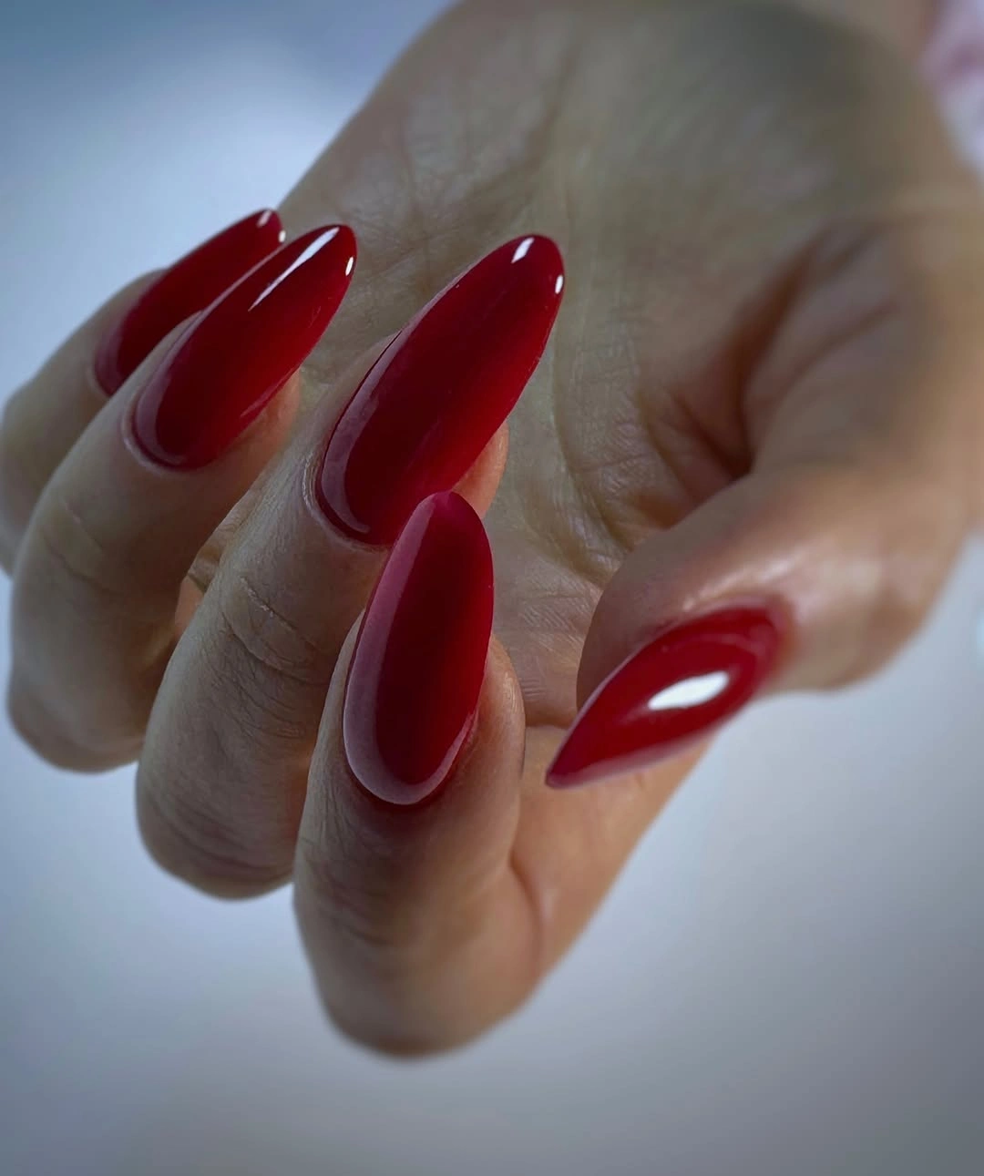 Medium stiletto nails in glossy red with a narrow pale outline