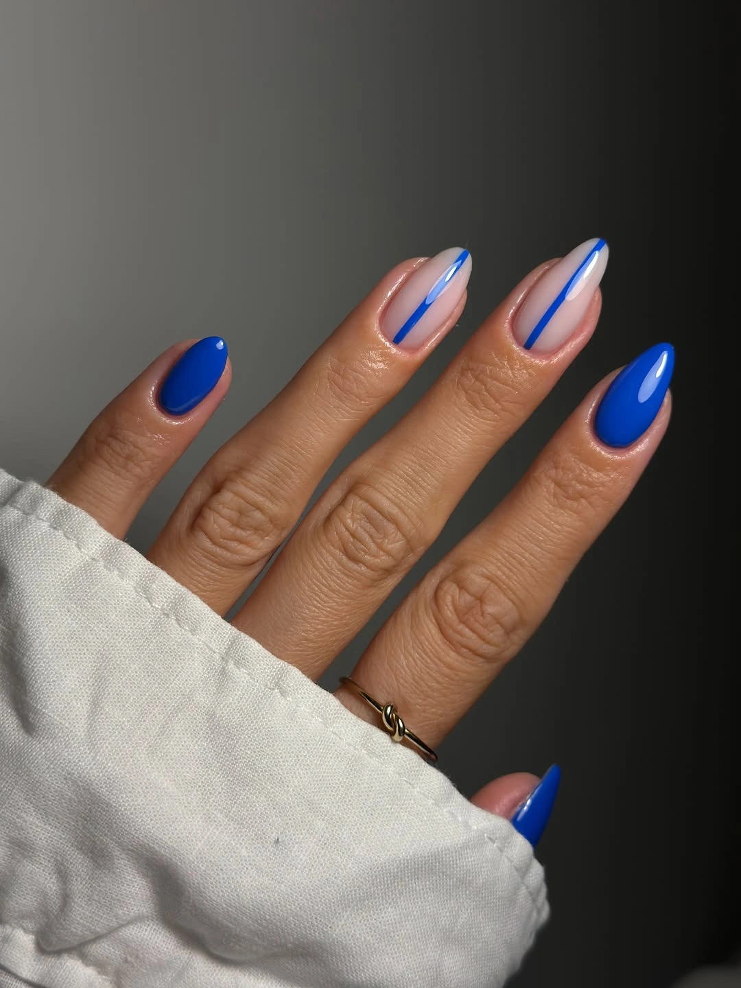 Long almond nails with a sheer pink base and vivid blue French tips