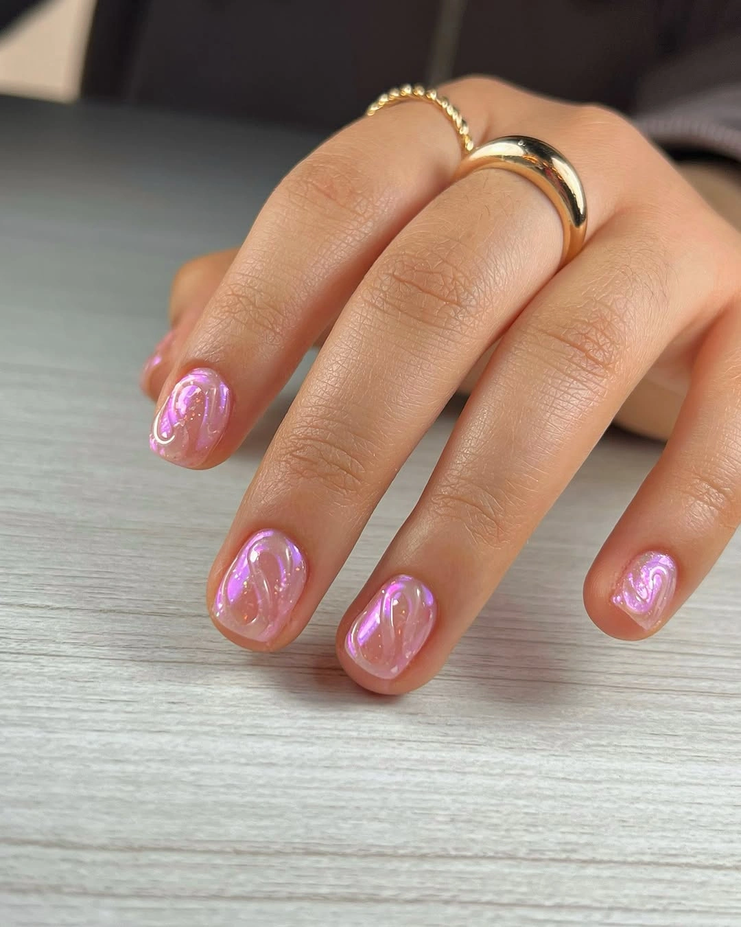 Short rounded nails with translucent pink bases and bright pink swirl accents