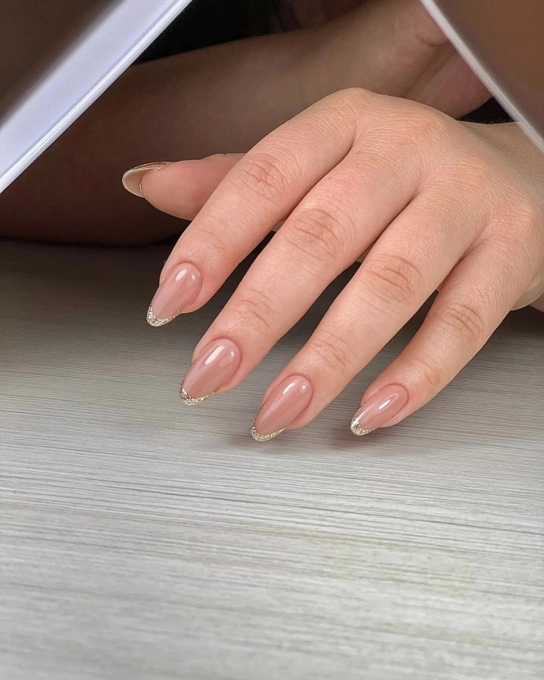 Medium almond nails in translucent nude pink with a minimal light tip