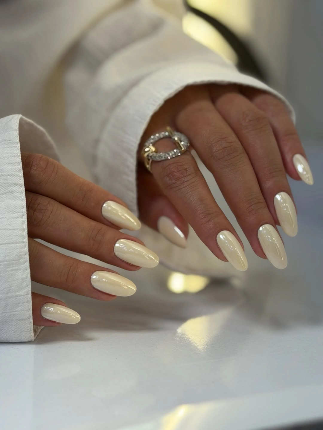 Long almond nails in a glossy cream-white neutral
