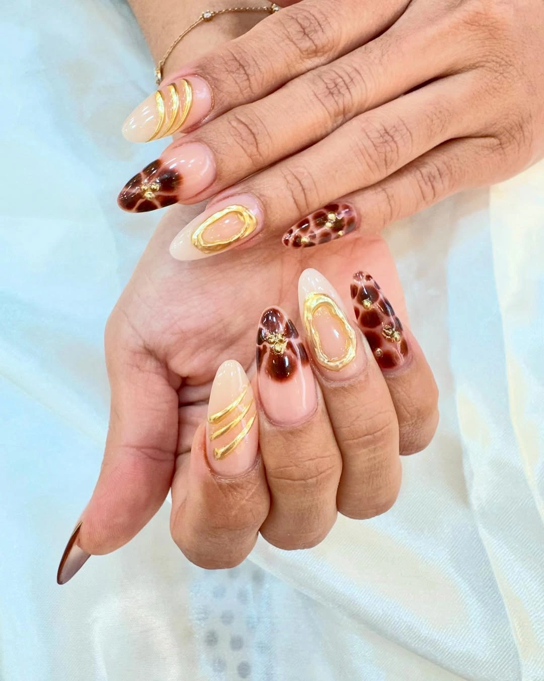Nude almond nails with brown pattern and gold accents