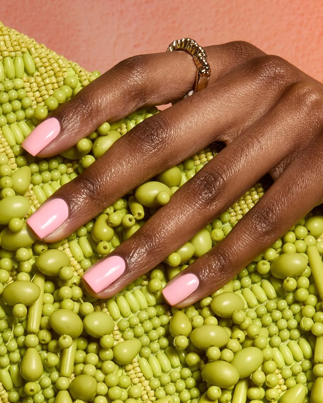 Short glossy soft pink nails against a vivid green background