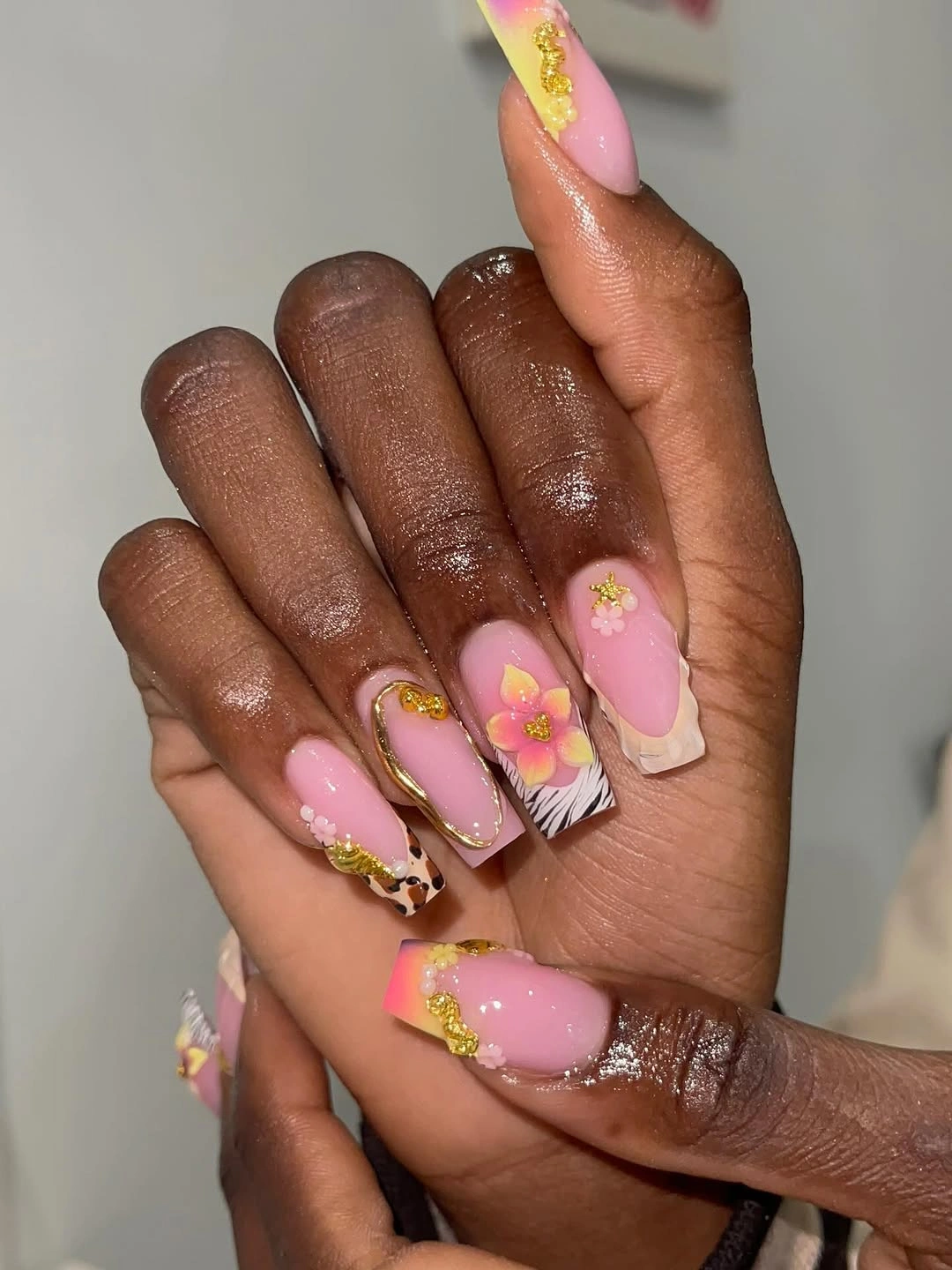 Long pink nails with large flower and gold accents